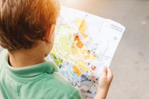 young boy reading map outside to promote offline activites