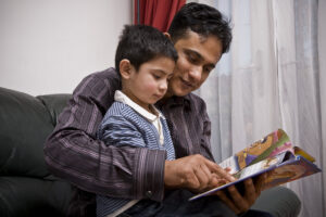 Father and son reading together at home. Both are engrossed in the story.